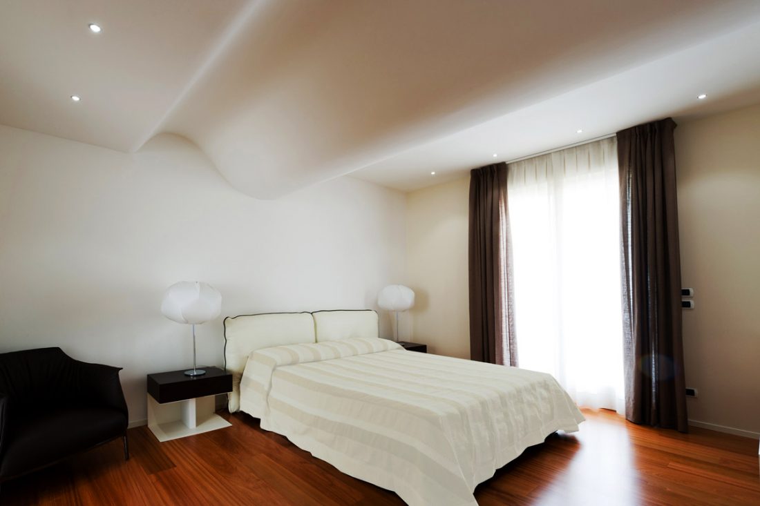 Una camera da letto matrimoniale bianca con il soffitto curvilineo che ricorda un'onda