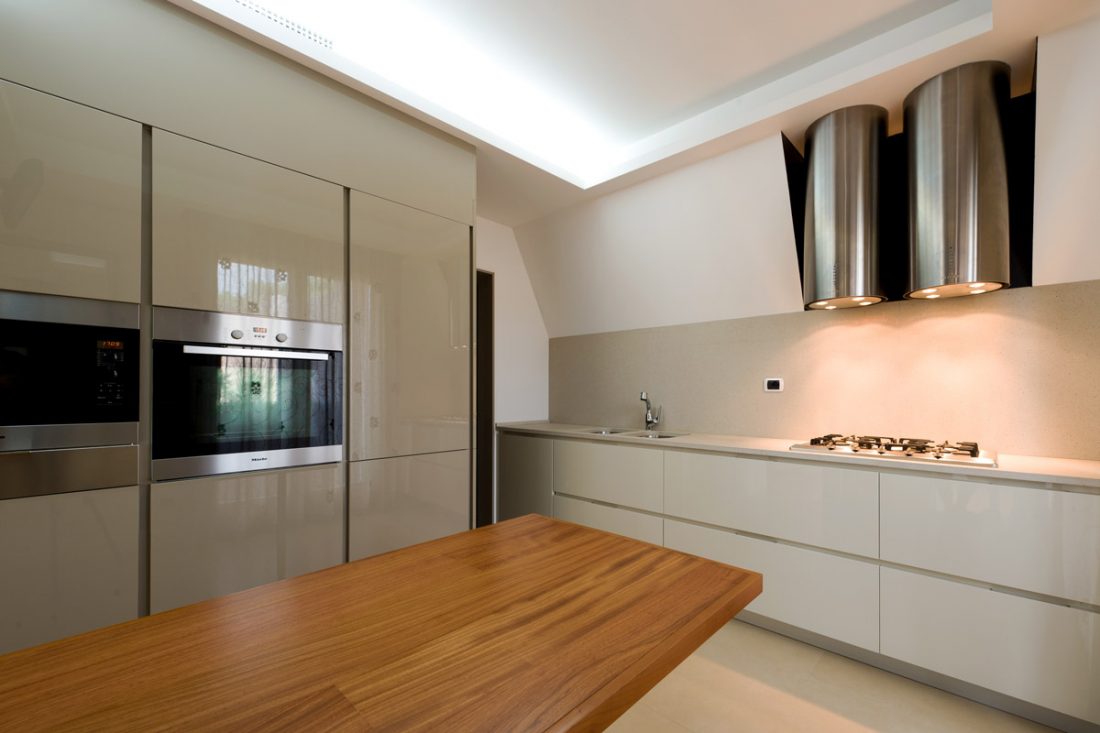 Una cucina moderna con colonne color tortora e un tavolo con piano in legno