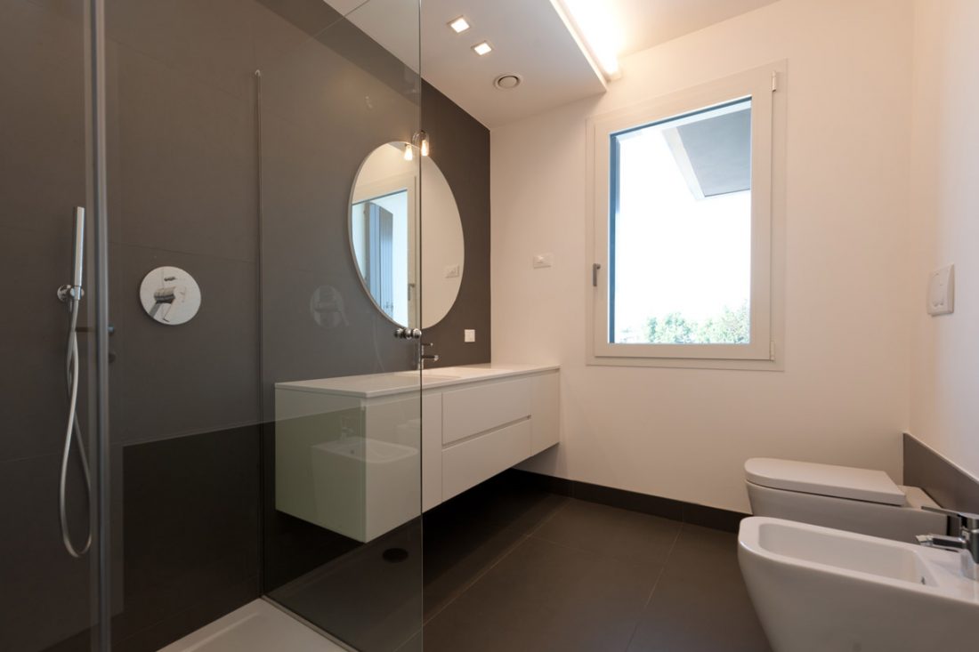 Rinnovo di un bagno con arredo moderno e specchio circolare